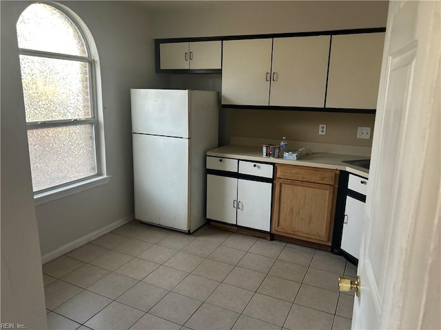 kitchen with baseboards, freestanding refrigerator, white cabinetry, and light countertops