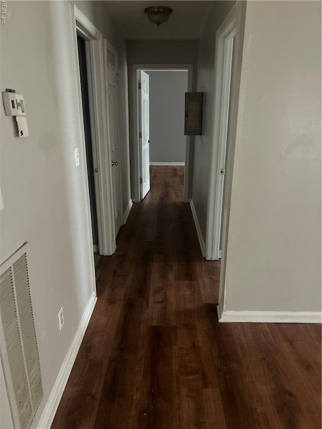 hall with visible vents, baseboards, and dark wood-style floors