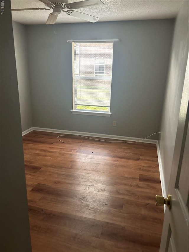 unfurnished room with baseboards, a ceiling fan, and wood finished floors
