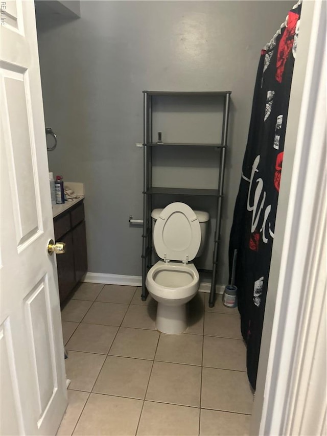 full bath with baseboards, tile patterned flooring, vanity, and toilet