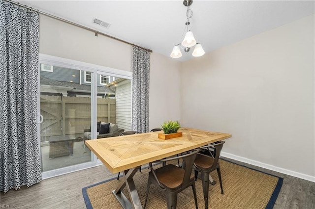 dining room featuring baseboards, visible vents, and wood finished floors