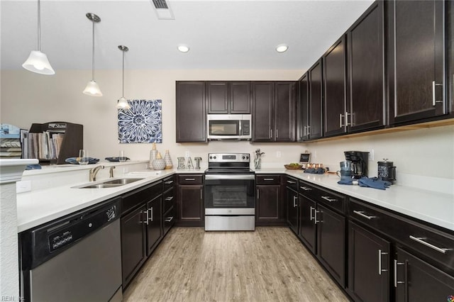 kitchen featuring appliances with stainless steel finishes, a sink, light wood-style flooring, a peninsula, and visible vents