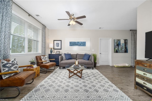 living room featuring a ceiling fan, baseboards, visible vents, and wood finished floors