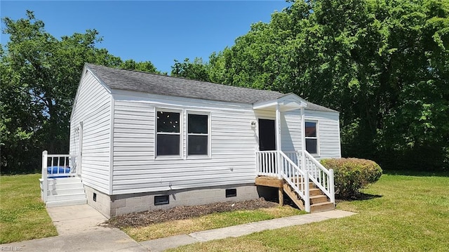 manufactured / mobile home with a shingled roof, a front yard, and crawl space