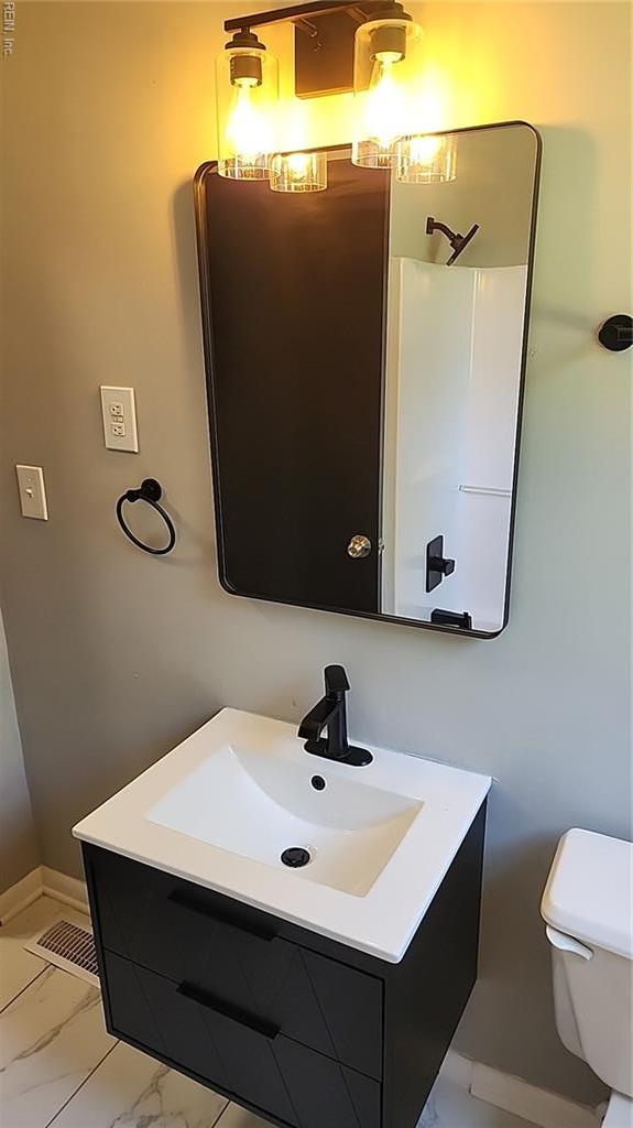 bathroom featuring baseboards, vanity, toilet, and marble finish floor