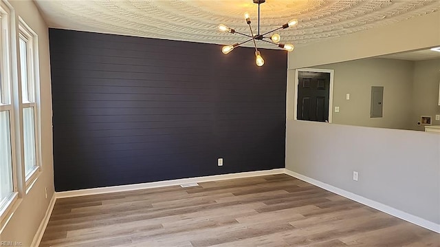 empty room with a wealth of natural light, wood finished floors, and electric panel