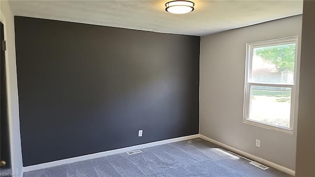 empty room with baseboards, carpet flooring, and visible vents