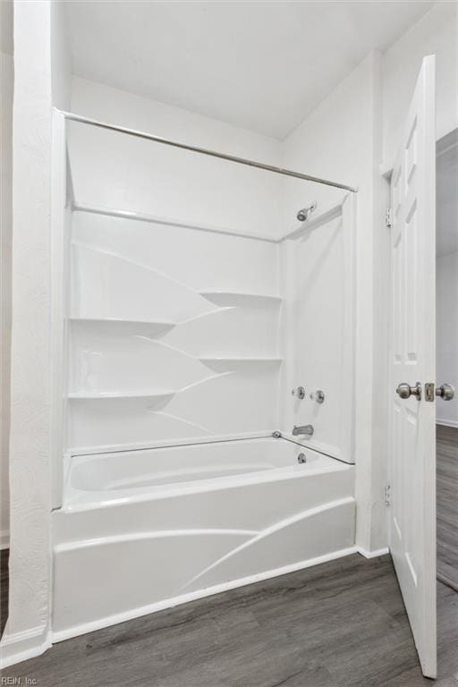 bathroom with baseboards, wood finished floors, and bathing tub / shower combination