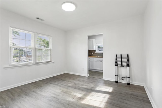 spare room with baseboards, dark wood finished floors, and visible vents