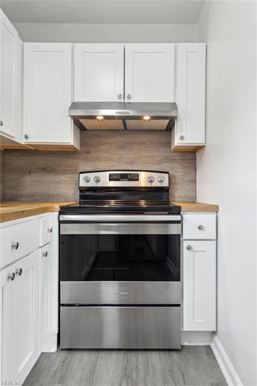 kitchen with wood counters, under cabinet range hood, light wood-type flooring, and stainless steel range with electric stovetop