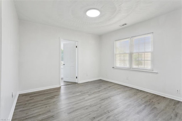 spare room featuring visible vents, baseboards, and wood finished floors
