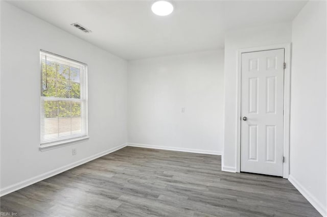 spare room with visible vents, baseboards, and wood finished floors