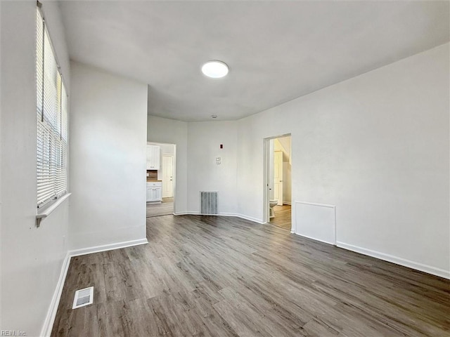 spare room with baseboards, wood finished floors, and visible vents