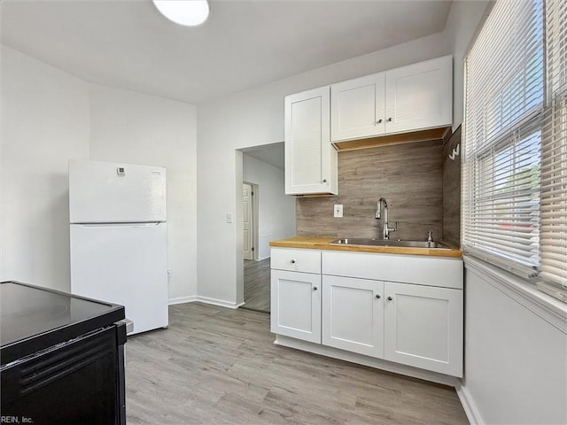 kitchen with freestanding refrigerator, decorative backsplash, white cabinets, and black range with electric stovetop
