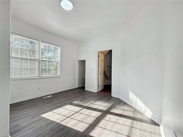 unfurnished bedroom with baseboards, wood finished floors, and visible vents