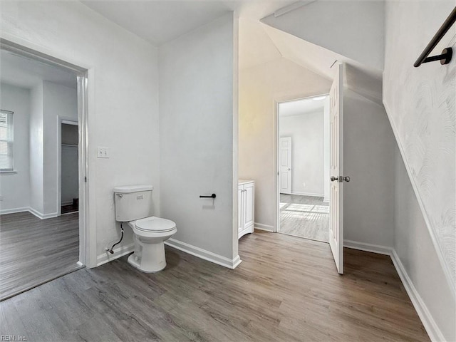 bathroom with baseboards, lofted ceiling, wood finished floors, and toilet