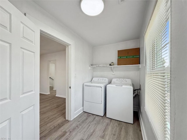 clothes washing area with laundry area, light wood-style flooring, independent washer and dryer, and baseboards