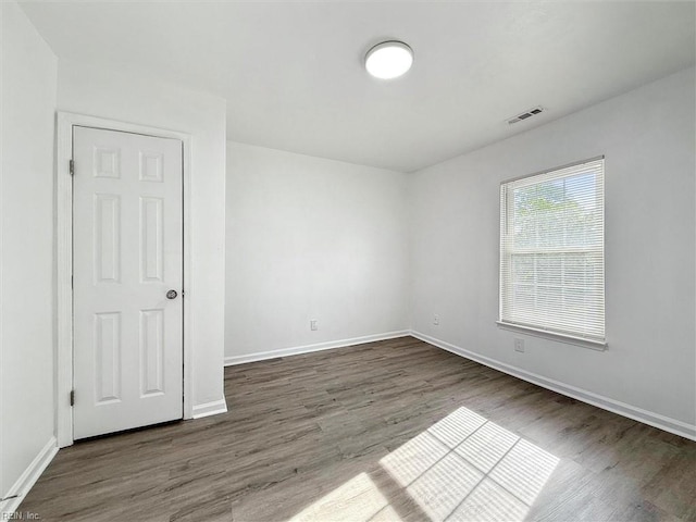 spare room featuring baseboards, wood finished floors, and visible vents