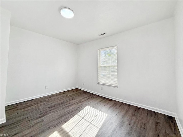 spare room with dark wood-style flooring, baseboards, and visible vents