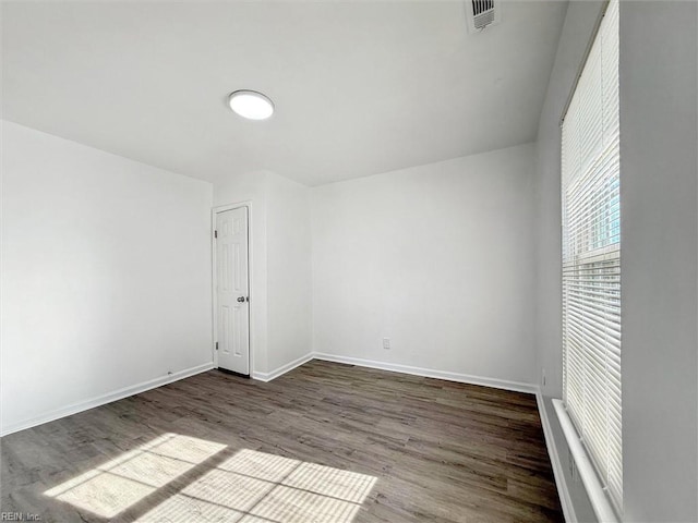 unfurnished room featuring baseboards, visible vents, and wood finished floors