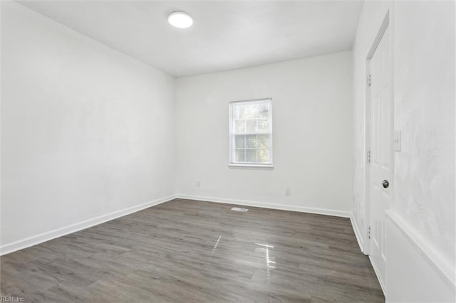 unfurnished room with baseboards and dark wood-style floors