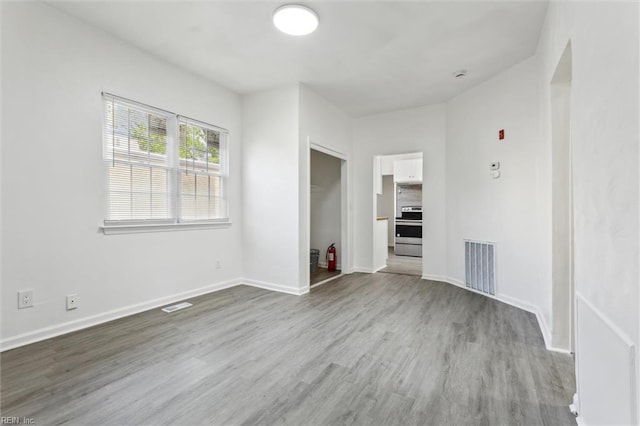unfurnished living room with baseboards, wood finished floors, and visible vents