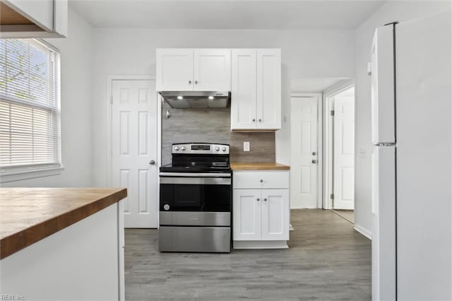 kitchen with white cabinets, wood counters, freestanding refrigerator, under cabinet range hood, and stainless steel electric stove