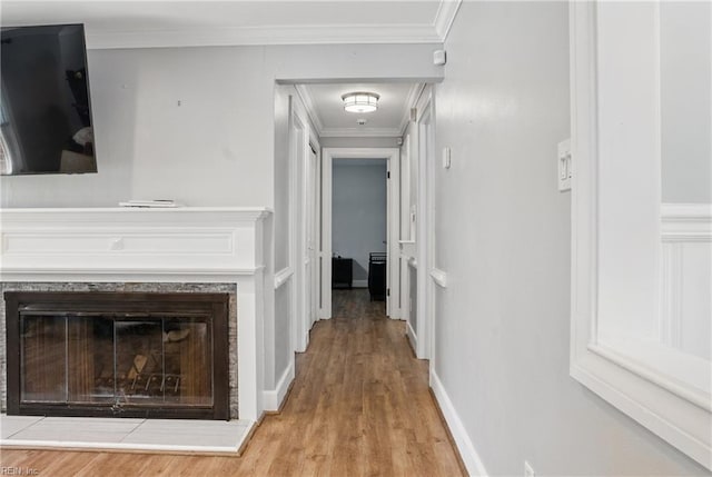 hall featuring baseboards, ornamental molding, and light wood-type flooring