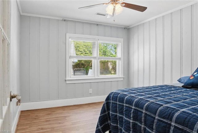 bedroom featuring ceiling fan, visible vents, crown molding, wood finished floors, and baseboards
