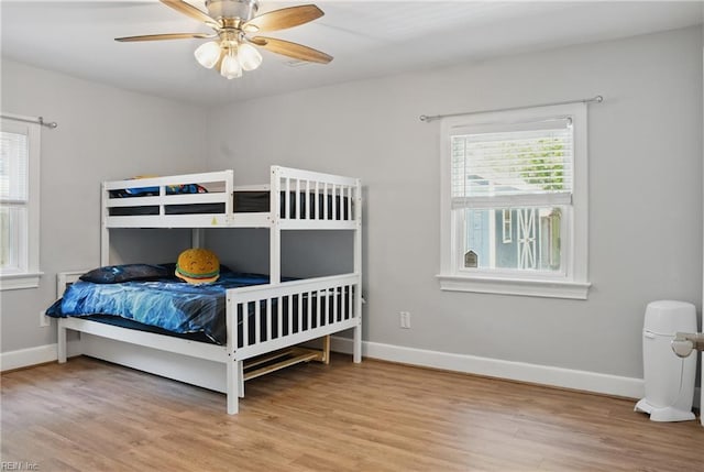 bedroom featuring a ceiling fan, baseboards, and wood finished floors