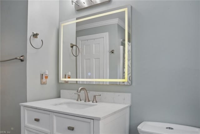 half bathroom with vanity, ornamental molding, and toilet