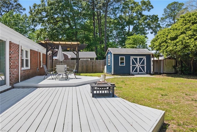 wooden terrace with a fenced backyard, a storage unit, a yard, a pergola, and a fire pit