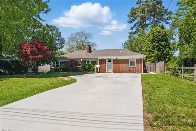 ranch-style home featuring fence, a front yard, a chimney, brick siding, and driveway