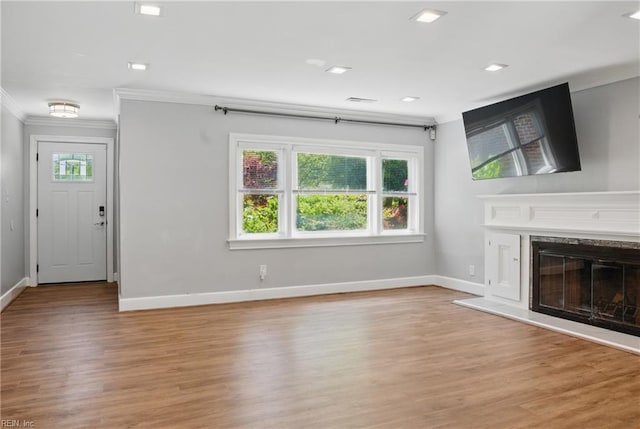 unfurnished living room featuring crown molding, baseboards, light wood-style flooring, and a high end fireplace