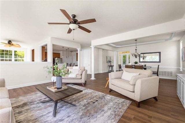 living room with dark wood-style flooring, ceiling fan with notable chandelier, and a wealth of natural light