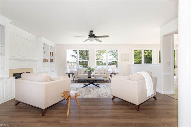 living area featuring dark wood-type flooring, baseboards, ceiling fan, and a fireplace
