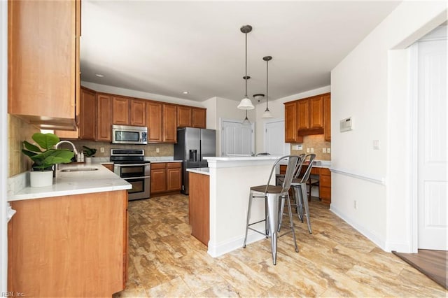 kitchen featuring appliances with stainless steel finishes, a sink, light countertops, a center island, and tasteful backsplash