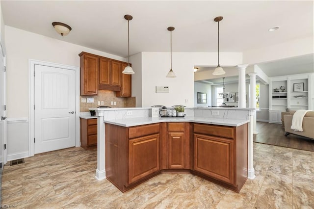 kitchen with brown cabinets, light countertops, open floor plan, backsplash, and ornate columns