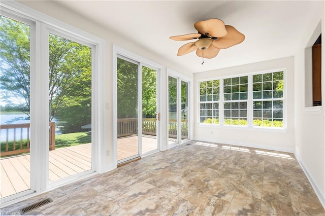 unfurnished sunroom with baseboards, visible vents, a wealth of natural light, and a deck