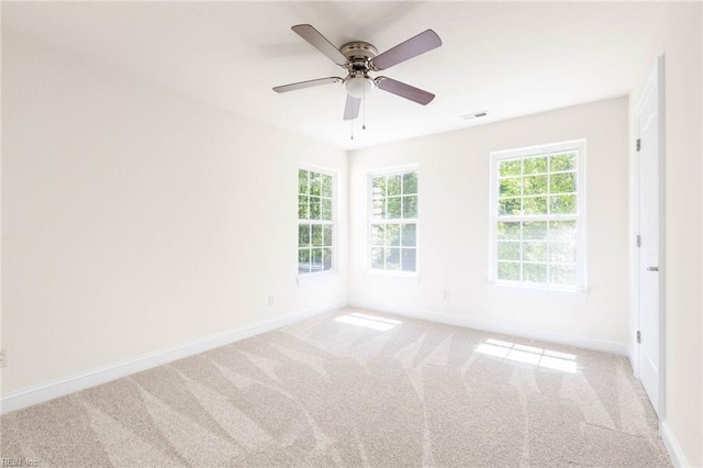 carpeted spare room featuring visible vents, a ceiling fan, and baseboards