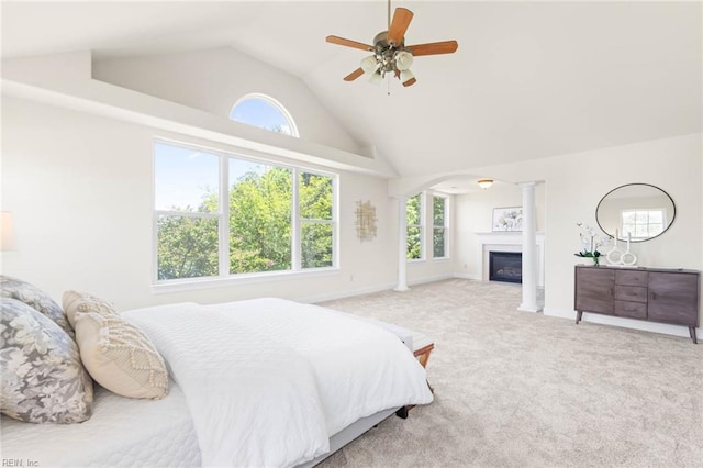 bedroom with a ceiling fan, carpet floors, baseboards, high vaulted ceiling, and a glass covered fireplace