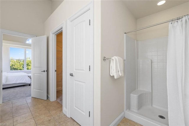 bathroom featuring baseboards, tile patterned flooring, ensuite bathroom, and a tile shower
