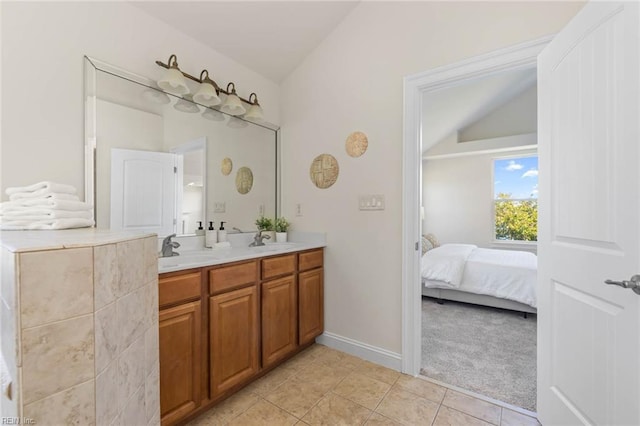 ensuite bathroom with double vanity, vaulted ceiling, a sink, tile patterned floors, and ensuite bathroom