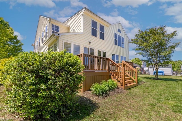 back of property with a lawn, a wooden deck, and stairs