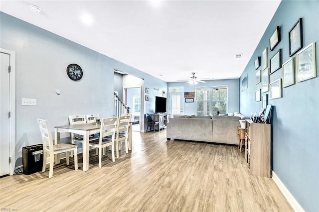living area with light wood-style floors, a ceiling fan, and baseboards