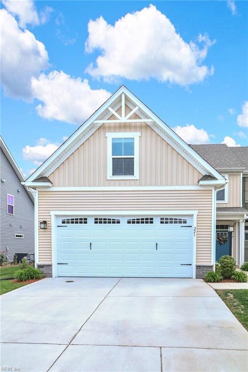 craftsman-style home featuring board and batten siding, driveway, stone siding, and a garage