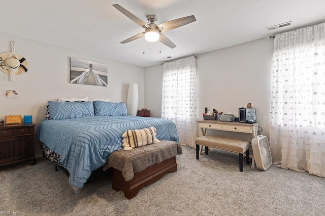 bedroom with light colored carpet, visible vents, and multiple windows