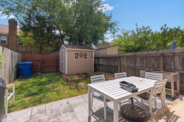 view of patio / terrace featuring a storage unit, outdoor dining space, a fenced backyard, a garden, and an outdoor structure