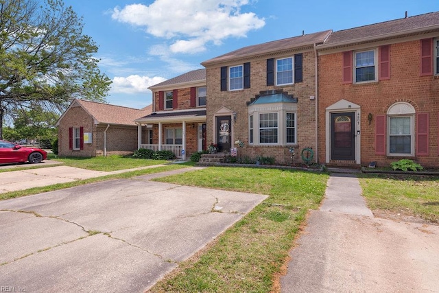 view of front of house with covered porch, a front lawn, and brick siding