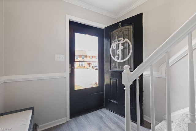 foyer with ornamental molding and wood finished floors